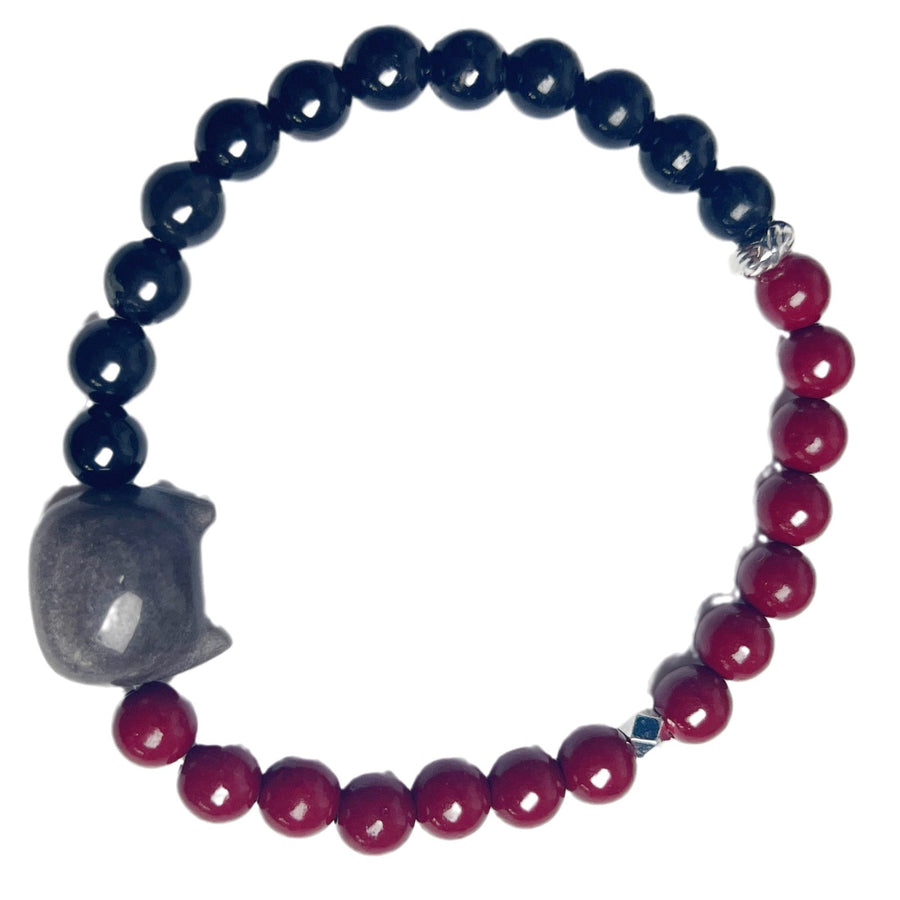 Hand wearing a bracelet with black and red beads and a grey cat charm
