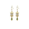 Gold-tone prayer wheel earrings with white jade cylinders and green drops hanging from a branch.
