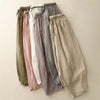 A flat lay of six pairs of loose linen harem pants in muted earth tones.