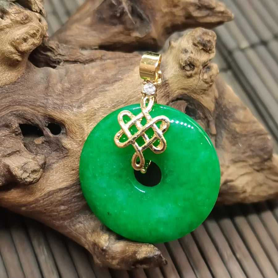 Close up of a green jade pendant with a gold tone bail on a wooden surface