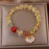 Gold beaded bracelet with a white jade ruyi charm on a box