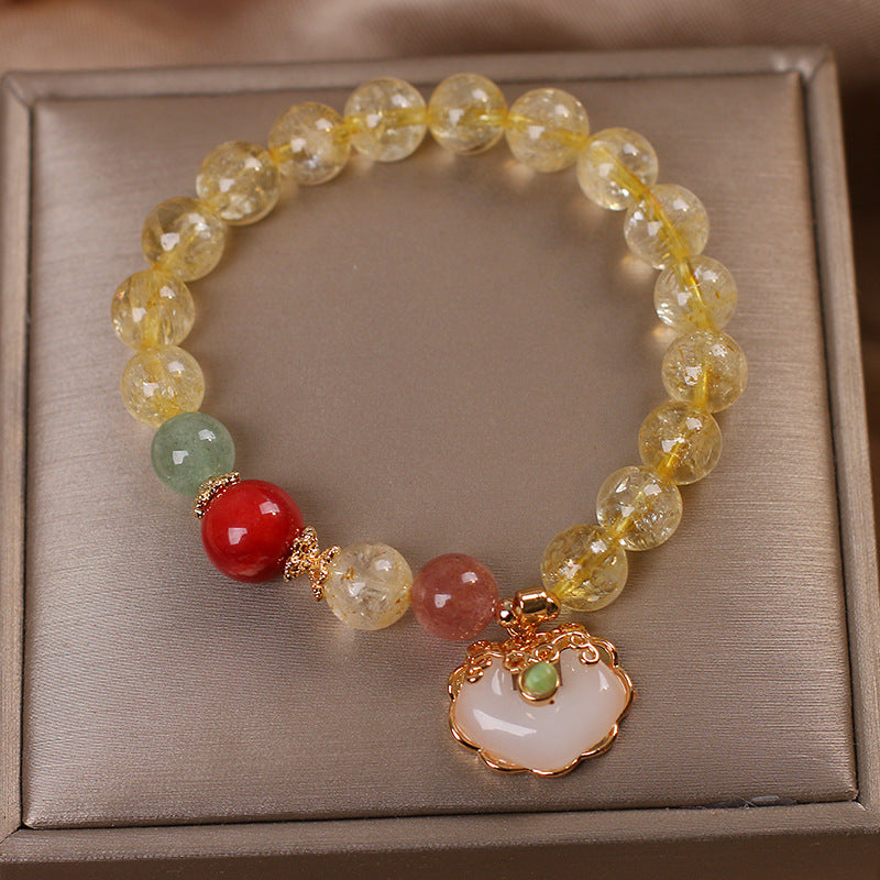 Gold beaded bracelet with a white jade ruyi charm on a box