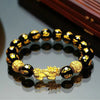 Gold-tone Pixiu charm on a black beaded bracelet with golden mantra characters