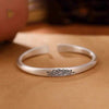 Matte silver-tone open cuff bracelet with an etched lotus flower design on the center band.
