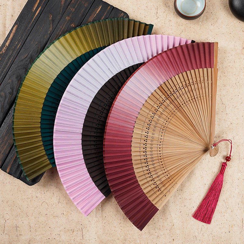 Group of colorful gradient bamboo folding fans with engraved handles