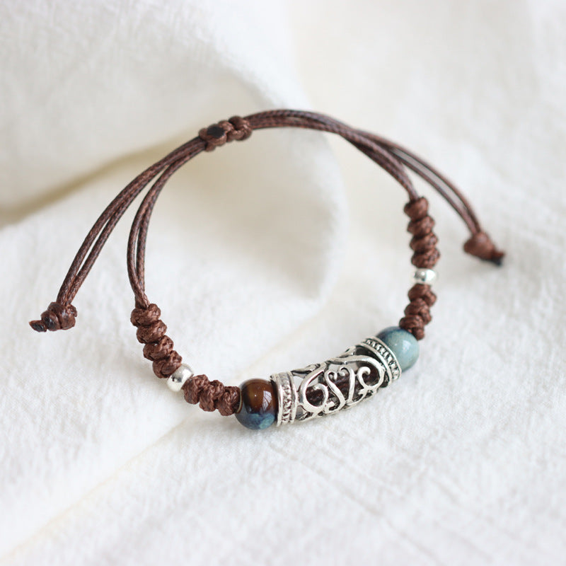 Close up of a brown woven bracelet with silver tone metal and blue ceramic beads