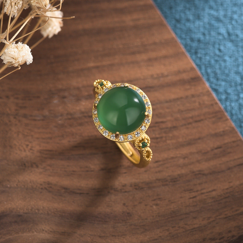 Close up view of a green jade ring with gold accents on a wooden surface