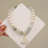 Close up of pearl and green bead bracelet on white card