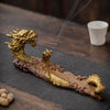 Gold-tone dragon shaped ceramic incense burner holding a stick of incense