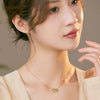 Close up of a woman wearing a silver necklace with a green jade and bamboo charm