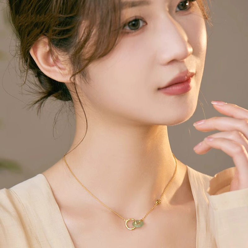 Close up of a woman wearing a silver necklace with a green jade and bamboo charm