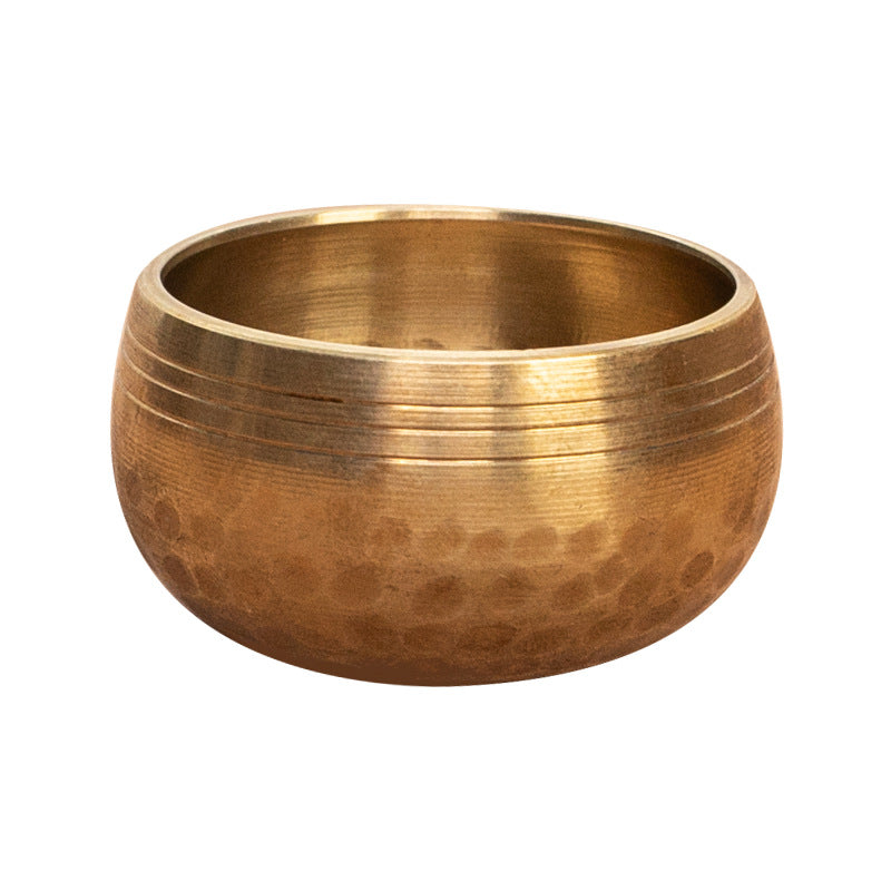 Close up of a small hammered copper singing bowl on a beige cloth background
