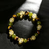 Close-up of a beaded bracelet with tiger eye, citrine, and green stones on a dark surface.