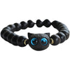Close-up of a black wood beaded bracelet with a carved cat face charm and blue eyes