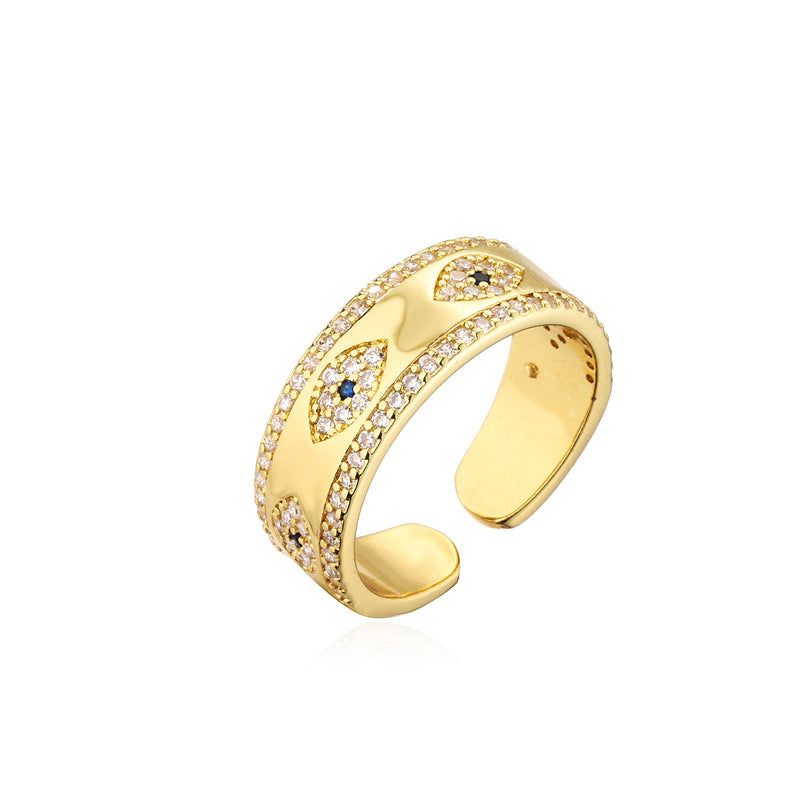 Gold tone copper ring with blue evil eye and clear stones on black background