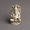 Small antique brass Ganesha statue sitting on a grey surface