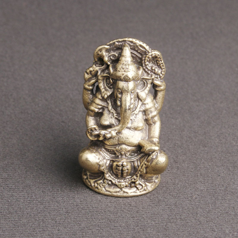 Small antique brass Ganesha statue sitting on a grey surface