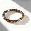 Close up of a tiger eye bead bracelet with a silver-tone lion charm on a wrist