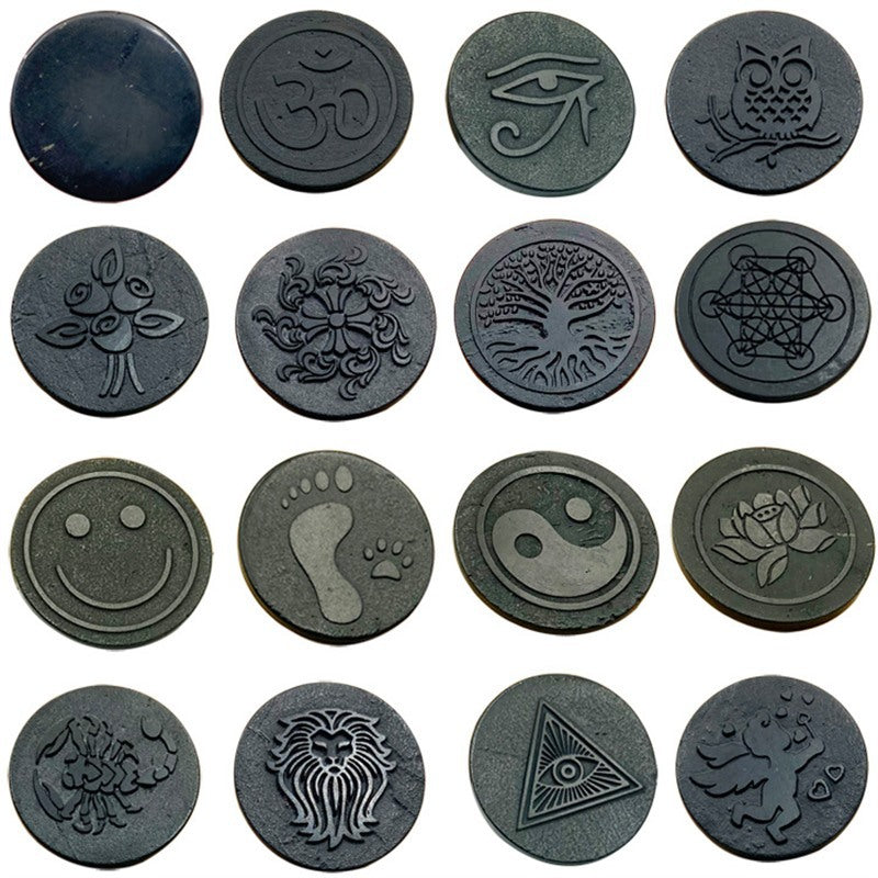 A collection of round dark metal stickers with various carved symbols including an owl, tree, and smiley face.