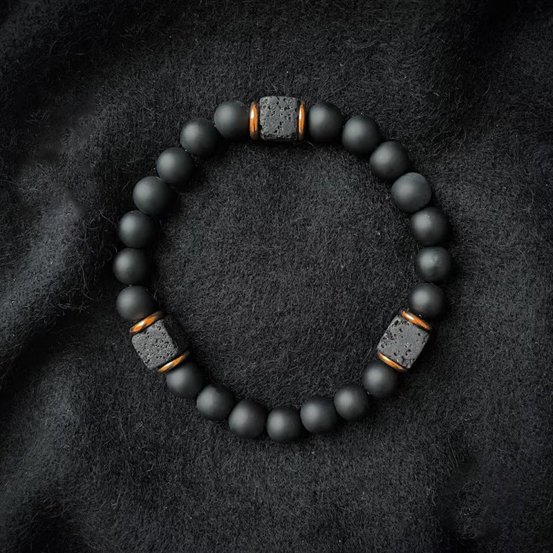 Matte black bead bracelet with square lava rock spacers on dark fabric