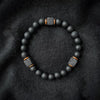 Matte black bead bracelet with square lava rock spacers on dark fabric