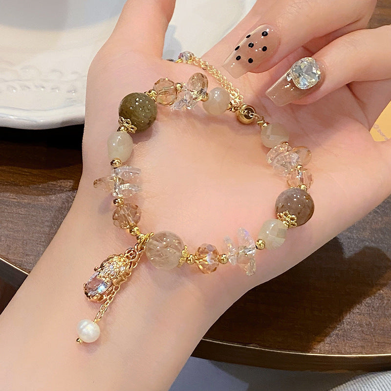 Close up of a hand wearing an adjustable beaded bracelet with a gold Pixiu charm