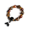 Close up of a brown and white striped sardonyx agate bracelet with black accents on a wooden surface