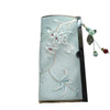 Light blue suede wallet with white floral embroidery and a beaded dangle charm