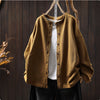 Relaxed fit solid color crew neck cardigan hanging on a wooden hanger