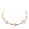 Close-up of a rose gold bracelet with pink crystal four-leaf clover charms on a purple background