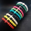 A collection of colorful beaded bracelets with cross charms arranged on a dark surface