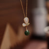 Gold tone necklace with a white butterfly pendant and a green jade bead drop