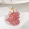 Close up of a pink strawberry quartz fox pendant on a gold chain