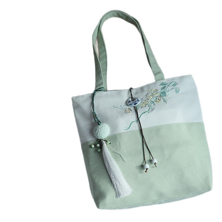 Light green and white canvas tote bag with floral embroidery and hanging tassel