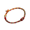 A close-up view of a multicolored braided rope bracelet with red wrapped ends on a white background