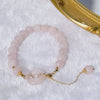 Close up of a pink rose quartz bracelet with a central peace buckle charm on a white textured surface