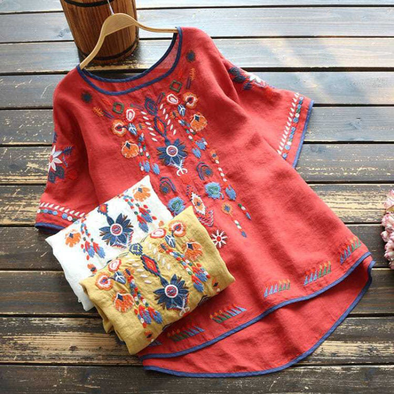 Red embroidered cotton linen t-shirt with floral patterns laid on wooden floor