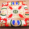 Close up view of red embroidered altar cloth with central Dharma wheel motif