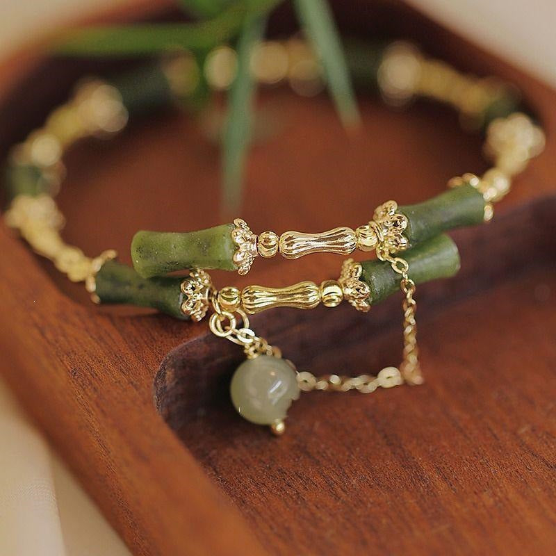 Close up of green bamboo bead bracelet with gold links and agate drop on wooden tray