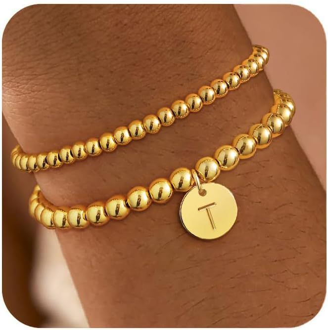 Two gold-tone beaded bracelets worn on a wrist, one with a letter T charm