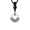A silver-tone copper pendant with a geometric pattern hanging from a black cord