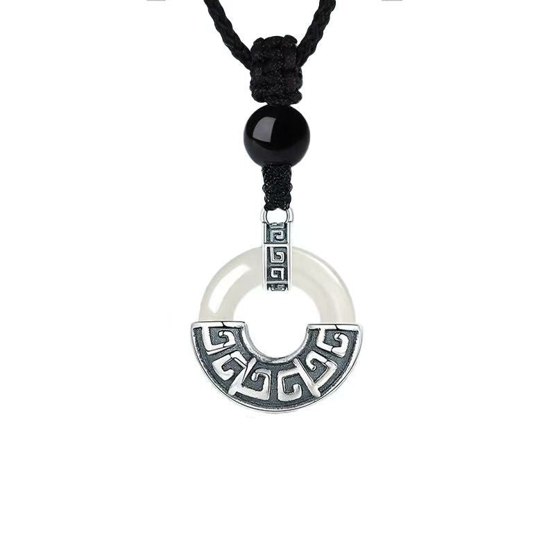 A silver-tone copper pendant with a geometric pattern hanging from a black cord