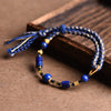 Blue braided rope bracelet with gold tone spacers and lazurite beads on wood
