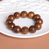 Close-up of a brown wooden beaded bracelet with black engraved Taoist characters resting on a white plate