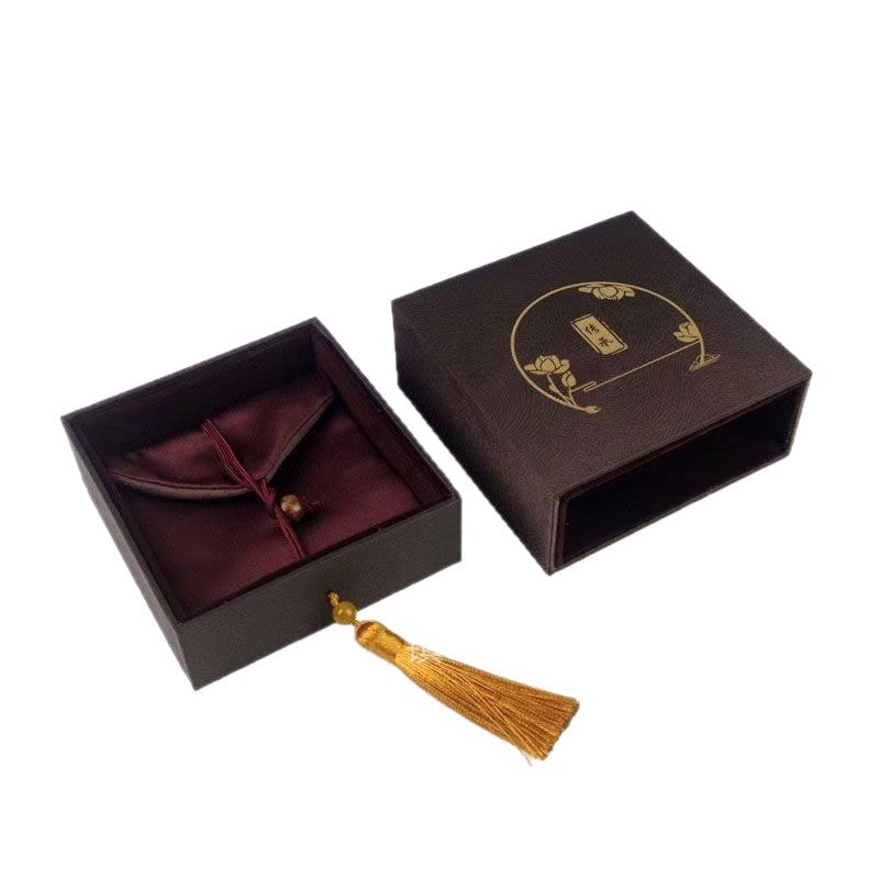 Open brown jewelry box showing maroon velvet interior and gold tassel