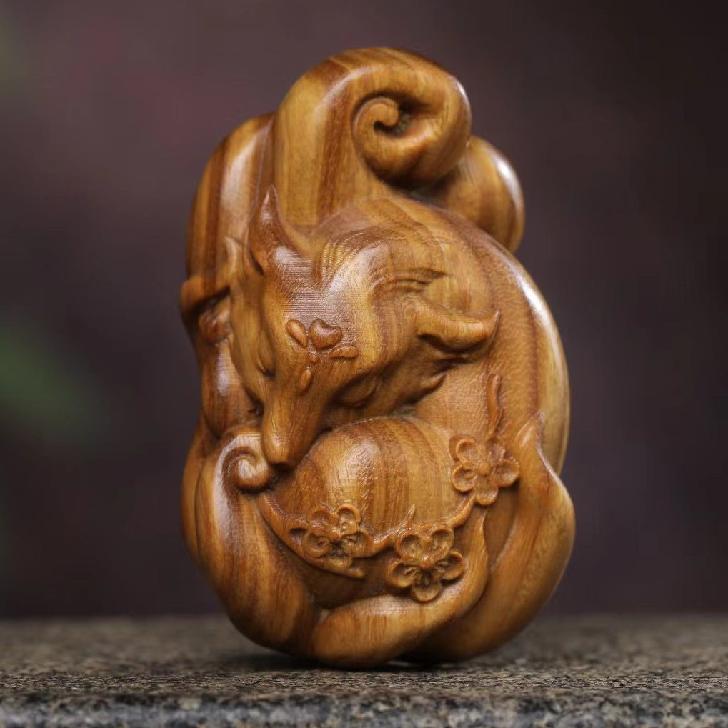 Close up view of a carved green sandalwood nine tailed fox figurine resting on a stone surface