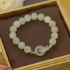 Close up of a white faux jade beaded bracelet with an interlocking ring charm in a box