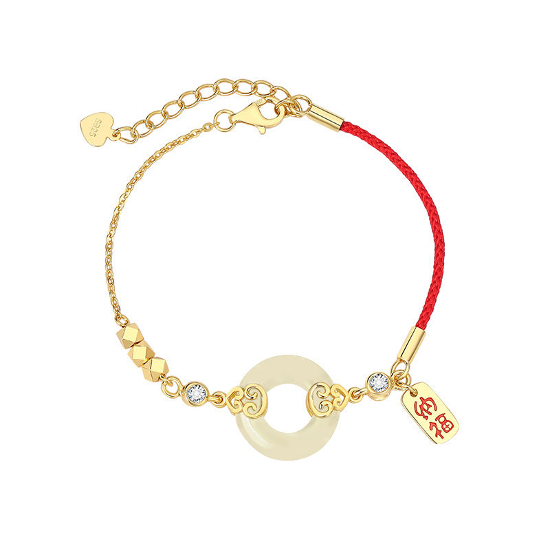 Close up of a silver bracelet with a jade donut charm and red string