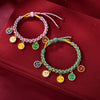 Two multicolored braided bracelets with gold-tone charms on a red background