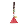 Hand holding a red triangular cinnabar keychain with a gold charm and beaded cord.